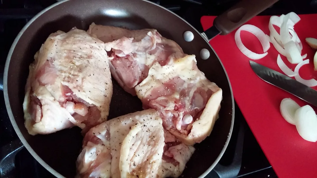Raw skin-on chicken thighs seasoned with salt and pepper, ready to cook