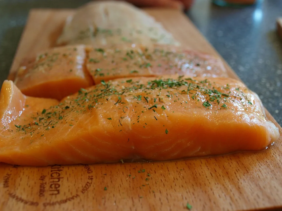 Raw skinless salmon fillets on a wooden board before curing