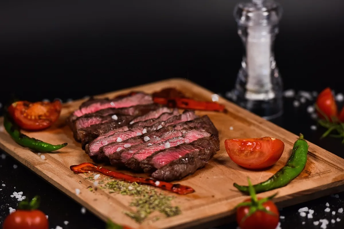 Medium-rare steak sliced against the grain on a wooden cutting board