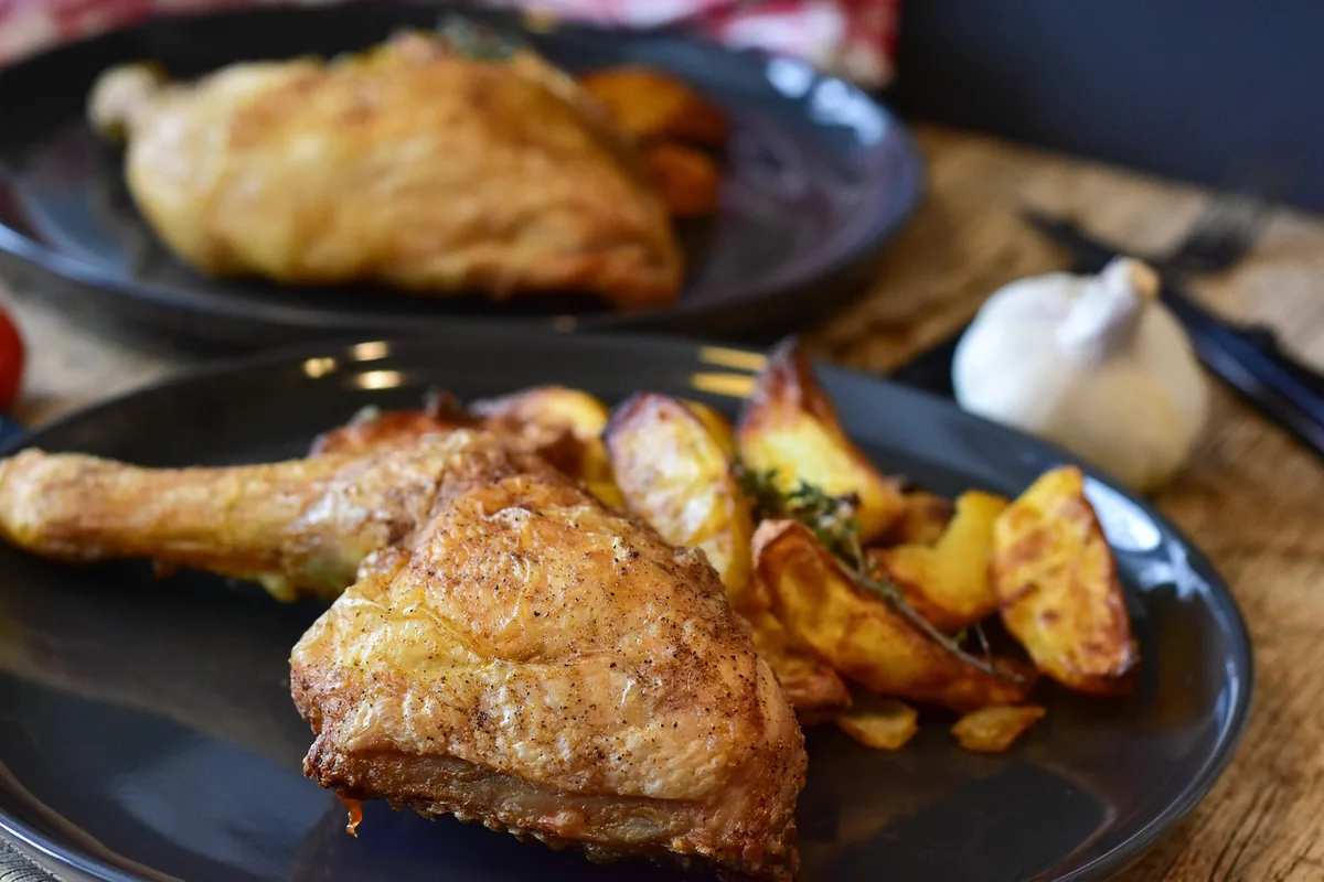 Golden chicken thigh with crisp skin and potato wedges, the result to aim for with this chicken thigh air fryer recipe