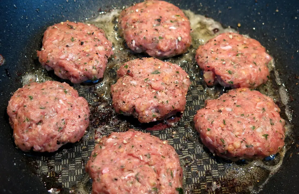 Ground beef patties browning in a frying pan