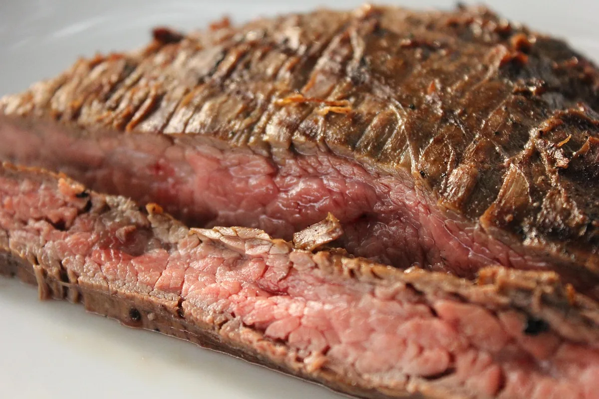Grilled steak sliced thinly against the grain, the way to serve bavette steak, with a pink center and browned crust