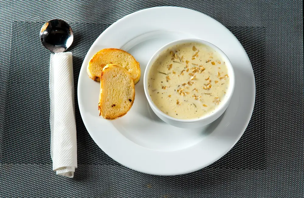 Cup of creamy chowder with toasted bread on a white plate