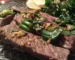Sliced seared steak topped with garlic and green onions, like the result of this flat iron steak recipe