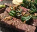 Sliced seared steak topped with garlic and green onions, like the result of this flat iron steak recipe