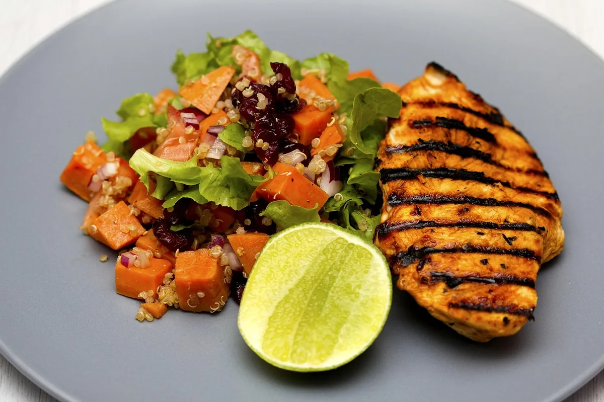 Golden chicken breast served with a sweet potato salad and a lime half, a simple way to serve sous vide chicken breast