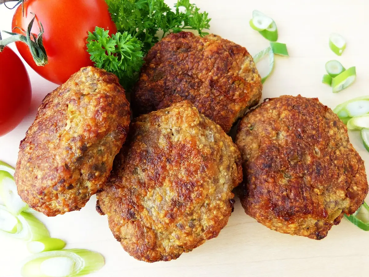 Browned ground beef meatballs with tomatoes and sliced green onions