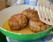 Browned meatballs in a green skillet with a spatula, like these gluten free meatballs