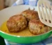 Browned meatballs in a green skillet with a spatula, like these gluten free meatballs