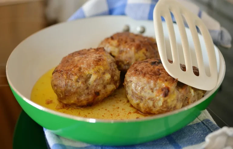 Browned meatballs in a green skillet with a spatula, like these gluten free meatballs
