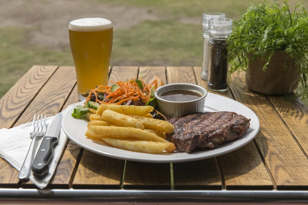Seared steak with fries and a cup of sauce, served bistro style as in this steak au poivre recipe