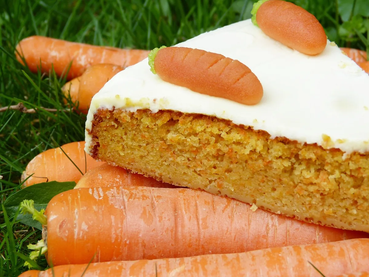 Slice of carrot cake with cream cheese frosting and a little decorative carrot, the classic finish for this carrot cake recipe