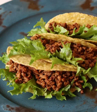 Ground beef tacos with lettuce on a blue plate, one of these healthy ground beef recipes