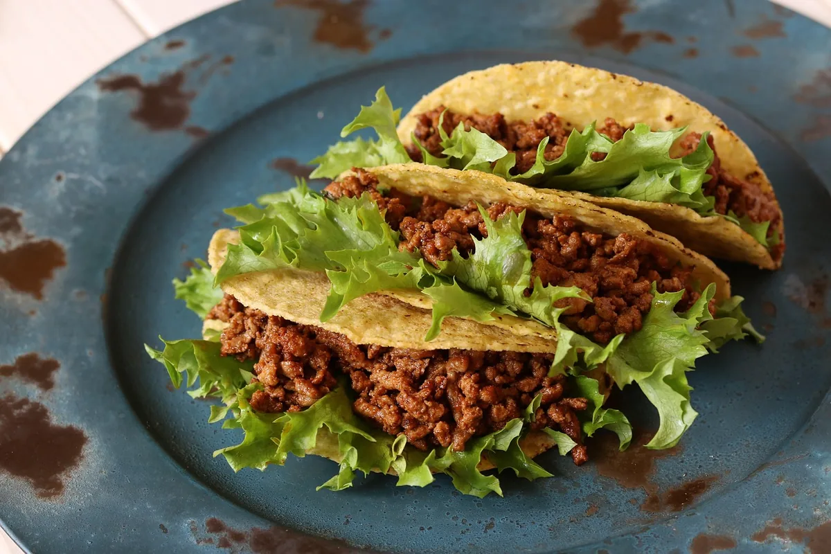 Ground beef tacos with lettuce on a blue plate, one of these healthy ground beef recipes