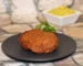 Golden pan-fried patty on a dark plate with a small bowl of mustard, the kind of crust to aim for with this salmon patty recipe