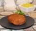 Golden pan-fried patty on a dark plate with a small bowl of mustard, the kind of crust to aim for with this salmon patty recipe