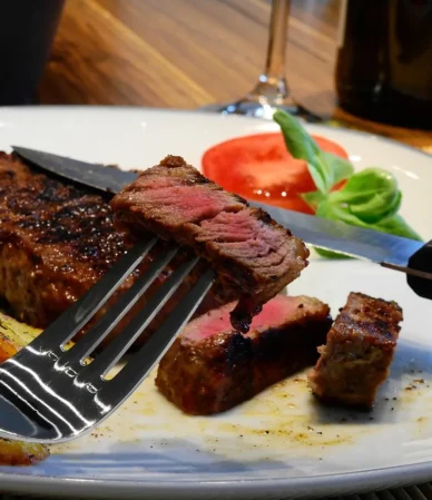 Steak cut open to show a pink center, served with roasted potatoes, like a reverse-seared chuck eye steak