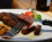 Steak cut open to show a pink center, served with roasted potatoes, like a reverse-seared chuck eye steak