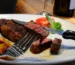 Steak cut open to show a pink center, served with roasted potatoes, like a reverse-seared chuck eye steak