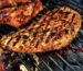 Seasoned smoked chicken breast with grill marks over hot coals