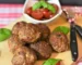 Oven baked meatballs on a board with basil and cherry tomatoes, showing how long to cook meatballs in oven