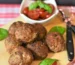 Oven baked meatballs on a board with basil and cherry tomatoes, showing how long to cook meatballs in oven