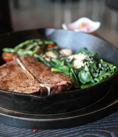 Cast iron skillet steak, a seared T-bone with spinach and mushrooms in the pan