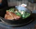 Cast iron skillet steak, a seared T-bone with spinach and mushrooms in the pan