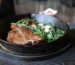 Cast iron skillet steak, a seared T-bone with spinach and mushrooms in the pan