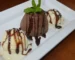 Single serve chocolate cake drizzled with chocolate sauce with vanilla ice cream and mint, like a chocolate mug cake turned out