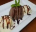 Single serve chocolate cake drizzled with chocolate sauce with vanilla ice cream and mint, like a chocolate mug cake turned out