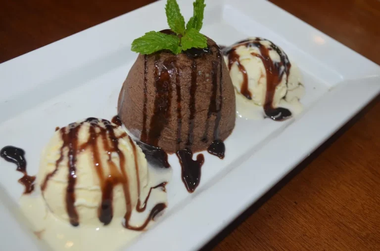 Single serve chocolate cake drizzled with chocolate sauce with vanilla ice cream and mint, like a chocolate mug cake turned out