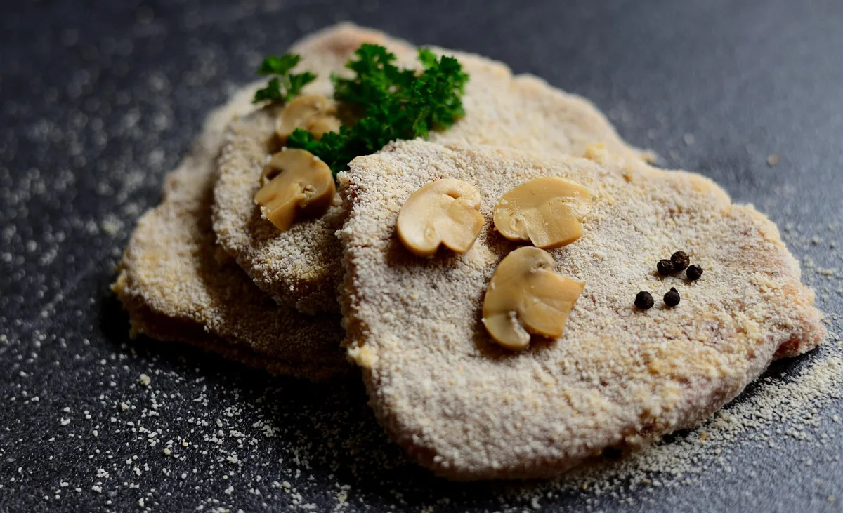 Thin cutlets coated in breadcrumbs, ready to cook, with mushroom slices and parsley
