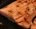 Salmon internal temp check: seared salmon fillet in a dark pan with opaque, flaking flesh