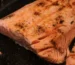 Salmon internal temp check: seared salmon fillet in a dark pan with opaque, flaking flesh