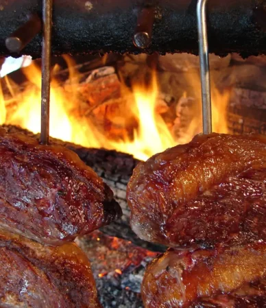 Picanha steak churrasco style: C-shaped beef on skewers grilling over an open wood fire