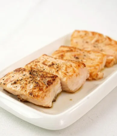 Air fry salmon recipe result: browned, flaky salmon fillet pieces on a white plate