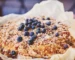 Baked blueberry dessert with a golden crumbly topping in a parchment-lined pan, similar to a blueberry dump cake
