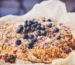 Baked blueberry dessert with a golden crumbly topping in a parchment-lined pan, similar to a blueberry dump cake