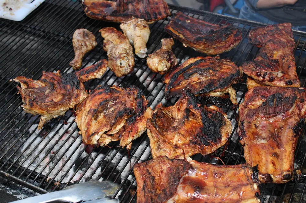 Chicken pieces browning on a barbecue grill grate