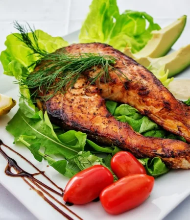 Salmon dinner ideas: grilled salmon on a green salad with avocado, cherry tomatoes and lemon