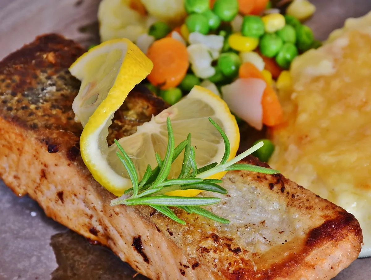 Pan-fried salmon fillet with crispy skin, lemon, rosemary and mixed vegetables