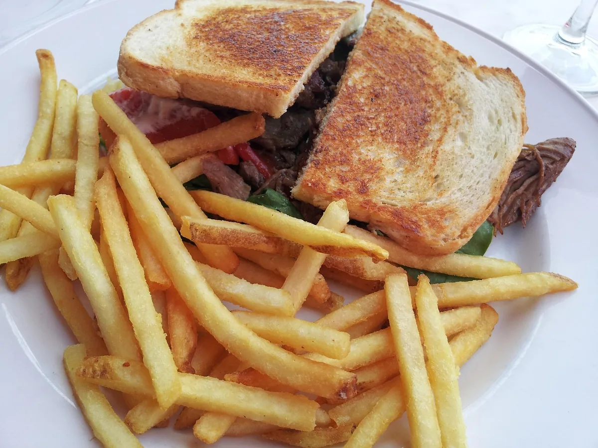 Toasted sandwich halves filled with sliced beef, served with French fries