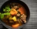 Crockpot beef stew with tender beef, carrots and potatoes in a dark bowl topped with parsley