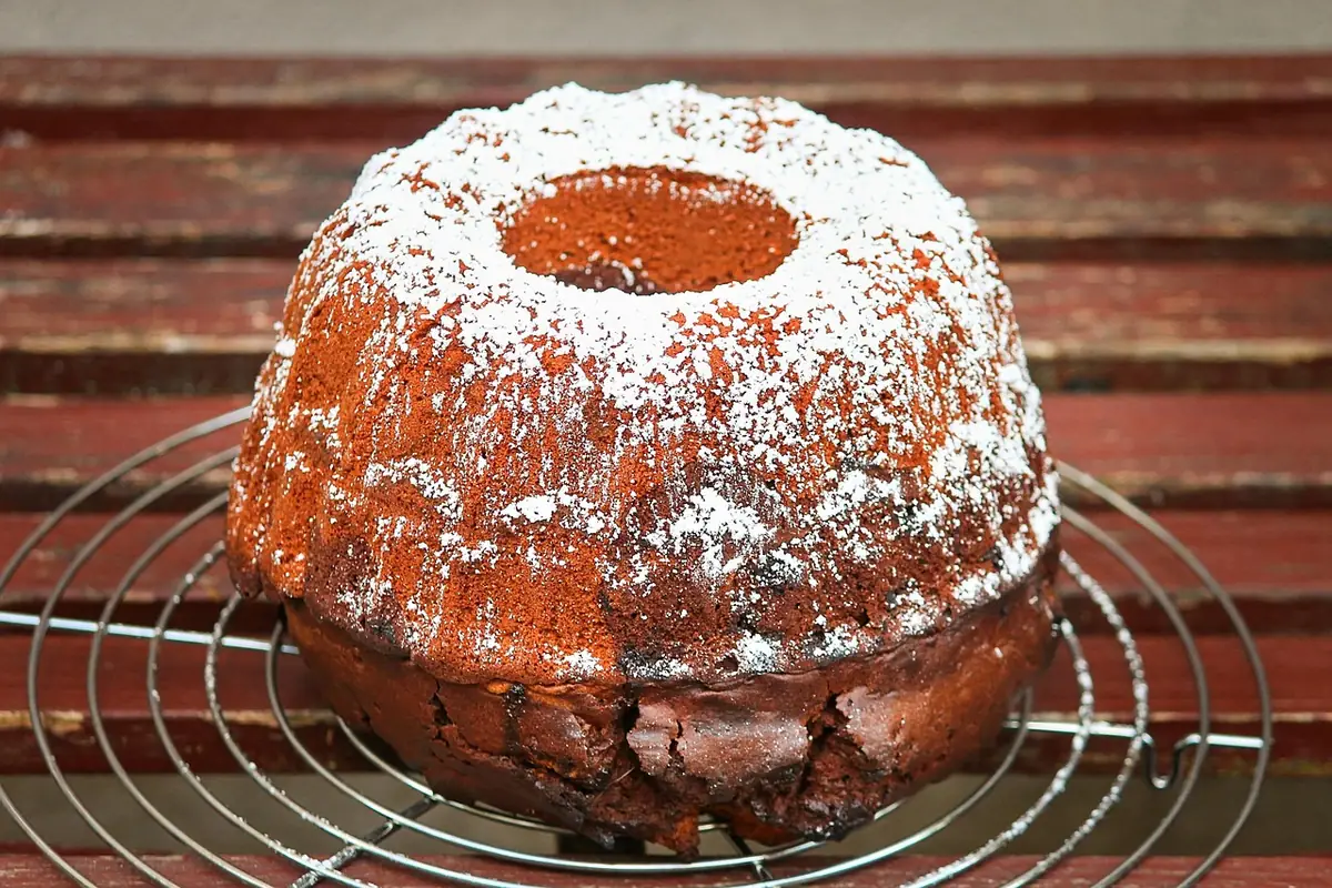Bundt cake dusted with powdered sugar on a cooling rack, similar to this sweet potato pound cake recipe