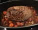 Seared beef roast braising with carrots in a dark roasting pot, similar to this chuck roast in the oven