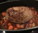 Seared beef roast braising with carrots in a dark roasting pot, similar to this chuck roast in the oven
