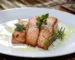 How to cook salmon: three seared salmon fillets with rosemary and olive oil on a white plate