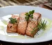 How to cook salmon: three seared salmon fillets with rosemary and olive oil on a white plate