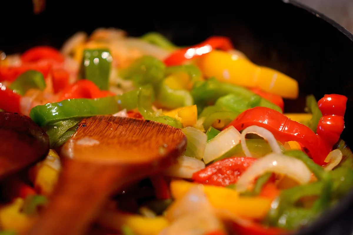 Bell pepper and onion strips cooking in a skillet for fajitas
